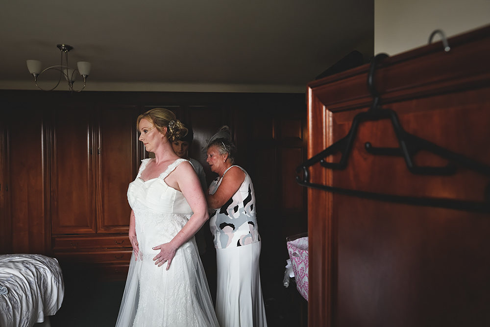 Mum helps bride into her wedding dress