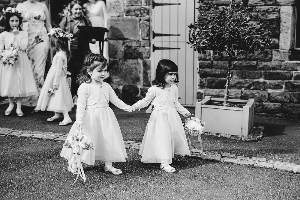 Two flower girls walk to the ceremony at The Ashes Barns in Staffordshire